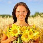 Smiling woman outside holding sunflowers